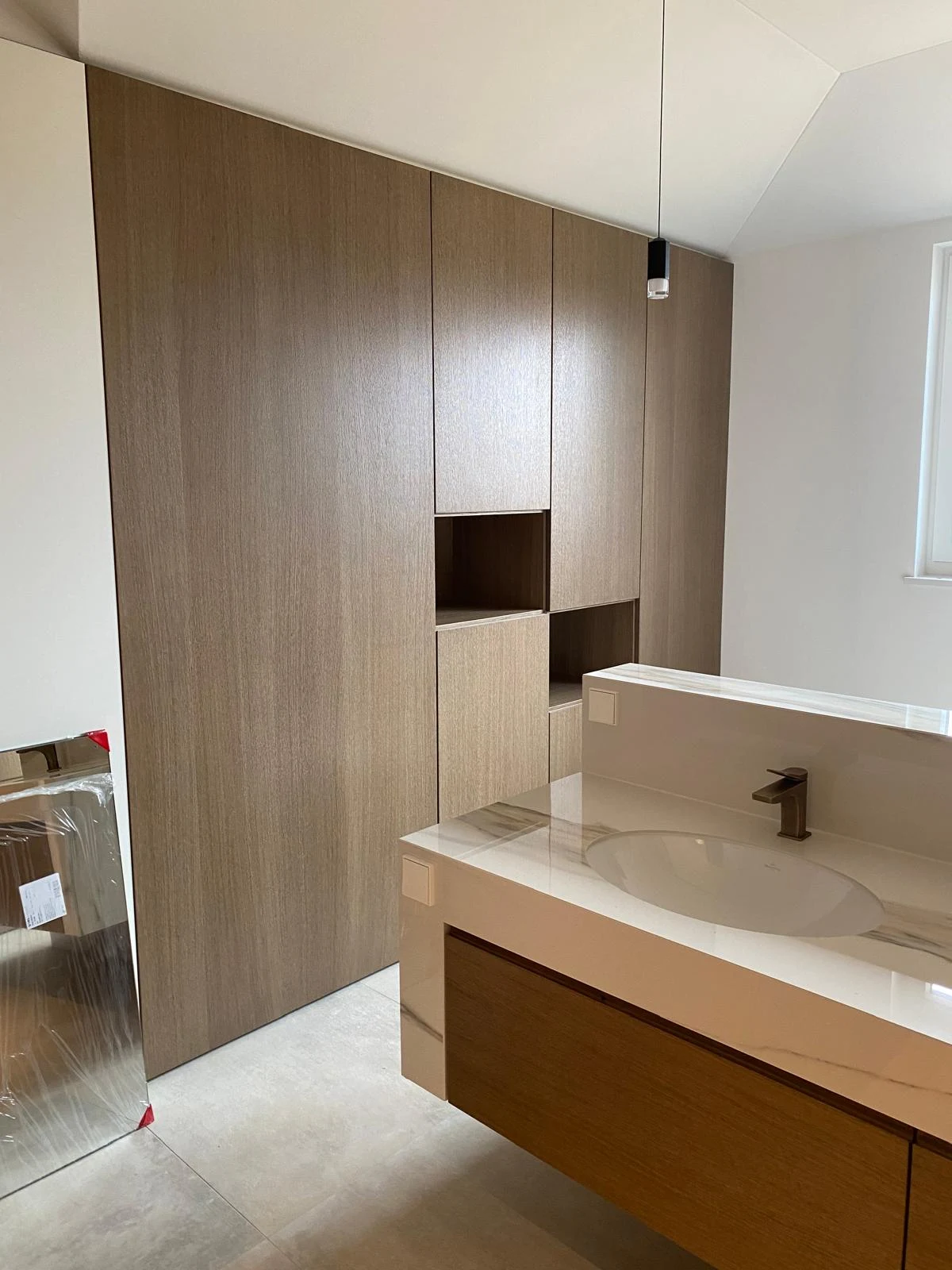 Badeinrichtung mit raumhohem Holzschrank und Waschtisch in Steinoptik